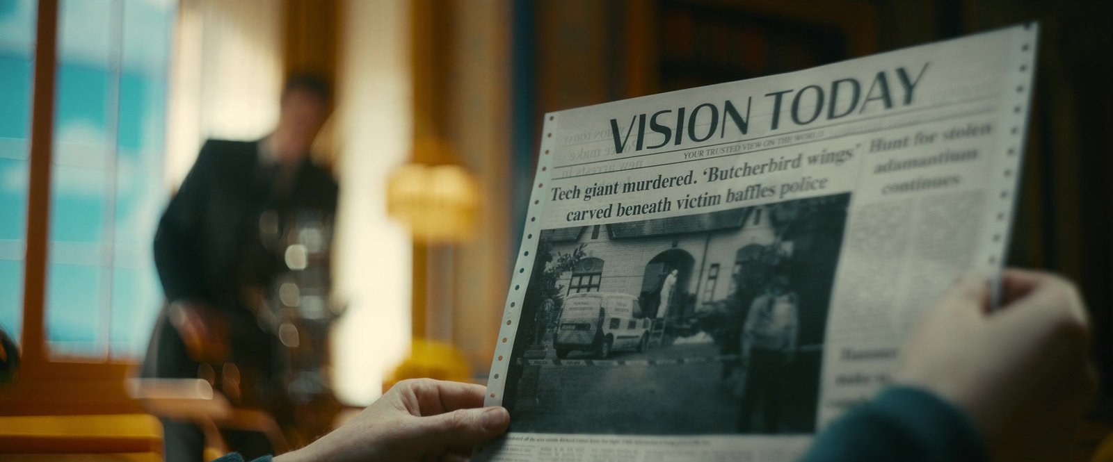 A hand holding a newspaper called Vision Today
